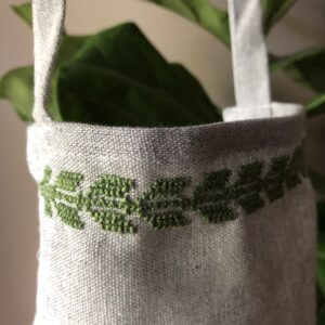 Apron stitched with green olive leaf motif.